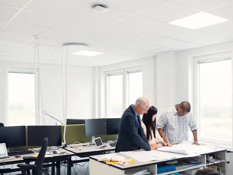 Drei Personen stehen in einem modernen Büro mit neu errichteten Trennwänden.